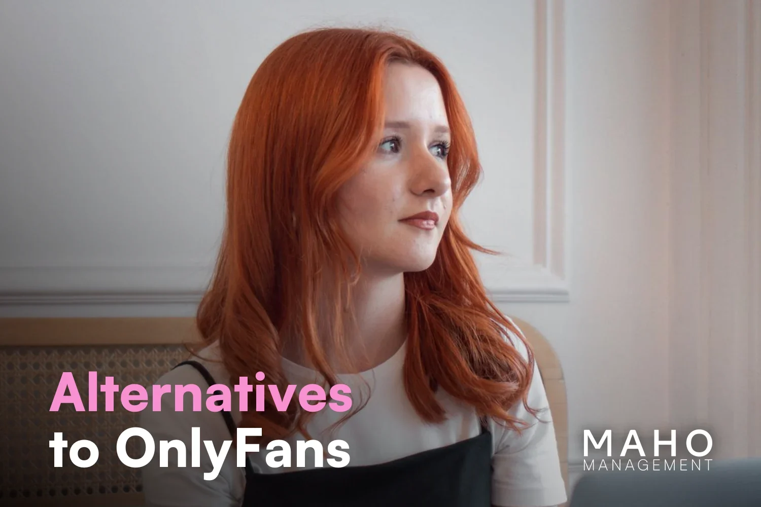 Red-haired creator looking up from her laptop in thought – weighing up OnlyFans alternatives