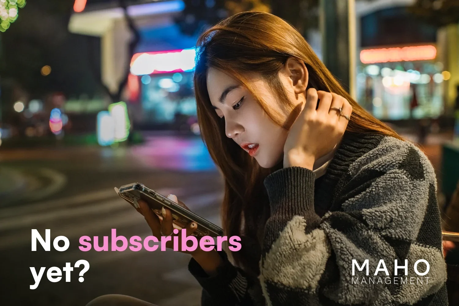 Young woman in the city at night looking worried at her phone (why an OnlyFans page gets no subscribers)